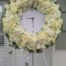 Large white floral wreath on a stand with cream roses and hydrangeas