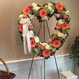Heart-shaped floral wreath on a stand with pink and white flowers