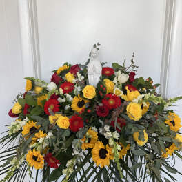 Large floral spray with red, yellow, and white flowers around a white statue