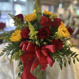 Bouquet of red roses, red carnations, and yellow flowers with a red ribbon