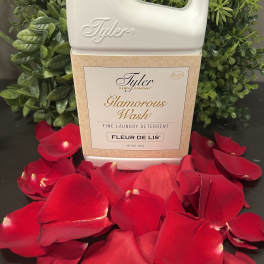 Tyler laundry detergent bottle surrounded by red rose petals and greenery
