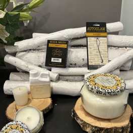 Candles and fragrance products arranged on wood slices with a few lily stems at left