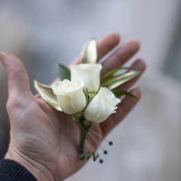 Small white rose boutonniere held in a hand