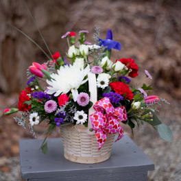 Mixed bouquet in a wicker basket with a pink heart ribbon
