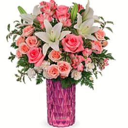 Pink roses and white lilies arranged in a pink vase