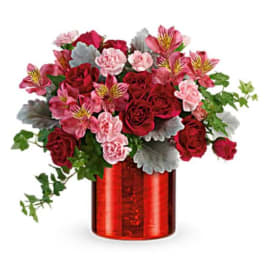 Red and pink flower arrangement in a red glass vase
