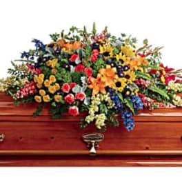 Colorful floral casket spray on a wooden coffin