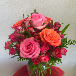 Pink and orange roses arranged in a clear glass vase