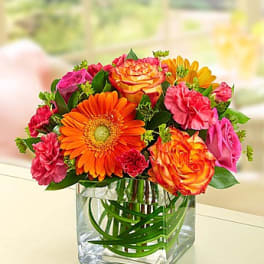 Bright mixed bouquet in a clear square glass vase