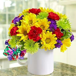 Bright mixed bouquet of daisies and carnations in a white mug