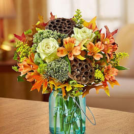 Autumn bouquet with white roses and orange flowers in a blue glass vase