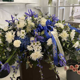 Large blue and white floral spray with ribbon in a container