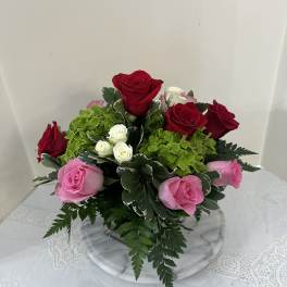 Bouquet of red and pink roses with green hydrangea in a glass vase