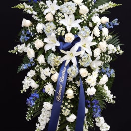 Large blue and white funeral spray with ribbon on an easel