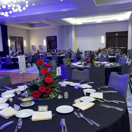 Round banquet tables with red rose centerpieces in a reception hall