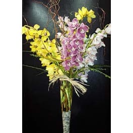 Tall bouquet of yellow, pink, and white orchids in a glass vase