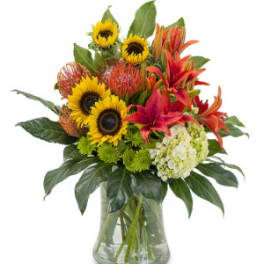 Mixed bouquet with sunflowers, lilies, and hydrangea in a glass vase
