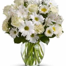 White bouquet of roses and daisies in a clear glass vase