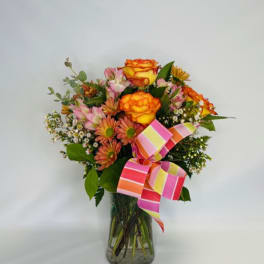 Bouquet of orange and pink flowers in a glass vase with a striped ribbon