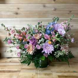 Mixed pastel bouquet in a dark vase on a wooden floor