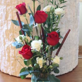 Tall arrangement of red and white roses in a glass vase