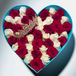 Heart-shaped turquoise box filled with red and white roses with a jeweled crown on top