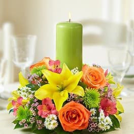Floral centerpiece with a green pillar candle and bright mixed blooms