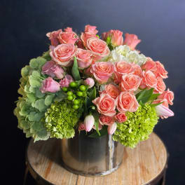 Pink roses and green hydrangeas arranged in a clear glass vase
