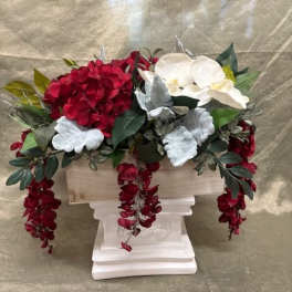Red and white floral arrangement in a white pedestal container