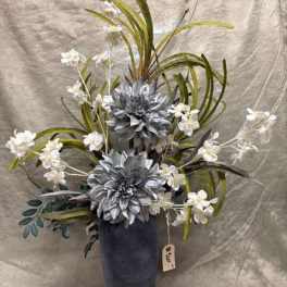 Tall floral arrangement with silver flowers and white blossoms in a dark vase