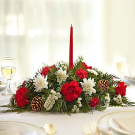 Holiday centerpiece with red and white flowers and a tall red candle
