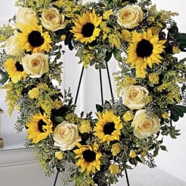 Heart-shaped floral wreath with sunflowers and cream roses on an easel