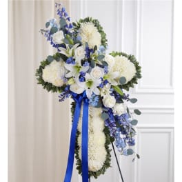 White floral cross arrangement with blue ribbon and blue accents