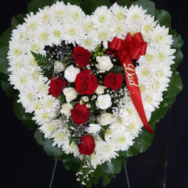 Heart-shaped floral wreath with white daisies and red roses, accented by a red ribbon
