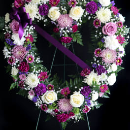 Heart-shaped floral wreath with purple ribbon on an easel