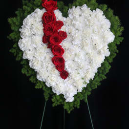 Heart-shaped floral spray of white carnations with red roses on a stand