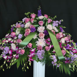 Large floral spray with pink roses and purple flowers on a stand