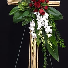 Floral cross with red roses and white orchids on a bamboo frame