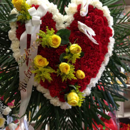 Heart-shaped red and white floral wreath with yellow roses and ribbon