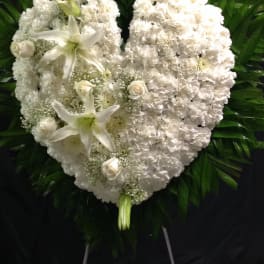 White heart-shaped funeral wreath with lilies and roses
