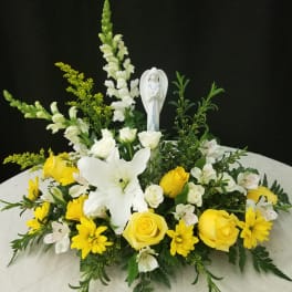 Yellow and white floral arrangement with a small angel figurine