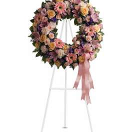Floral wreath on a white stand with pink ribbon