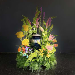 Tall floral arrangement with yellow roses, pink lilies, and purple spikes in a blue vase