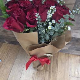 Bouquet of red roses with small white daisies wrapped in brown paper