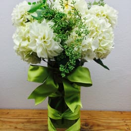 White flower bouquet in a glass vase with a green ribbon