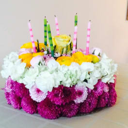 Round floral centerpiece with candles in pink, green, and white