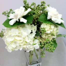 White hydrangea bouquet with white roses in a clear glass vase