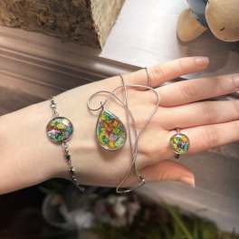 Hand wearing colorful resin jewelry with dried flowers