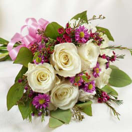 Bouquet of white roses and purple daisies tied with a pink ribbon