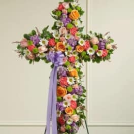 Cross-shaped floral standing spray with multicolored flowers and a lavender ribbon